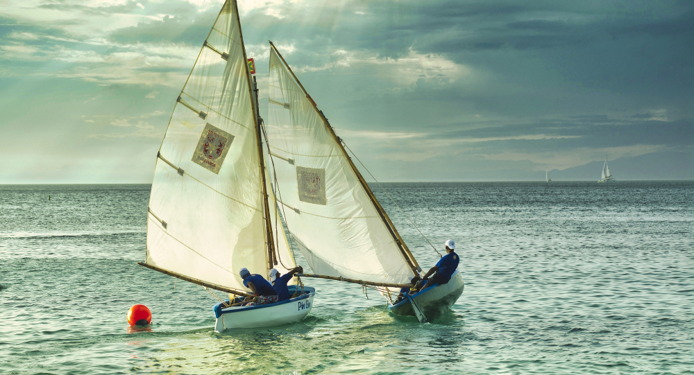 Traditional paraw outrigger sailboat on White Beach Boracay at golden hour, two passengers visible