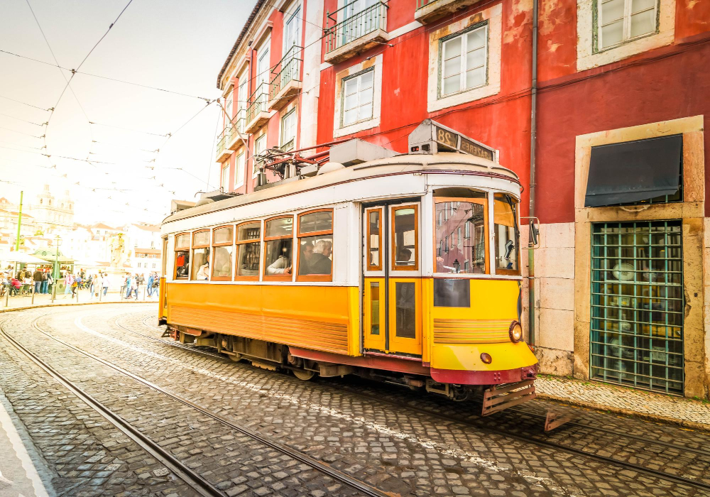 Yellow tram 28 on a cobbled Lisbon street with autumn light