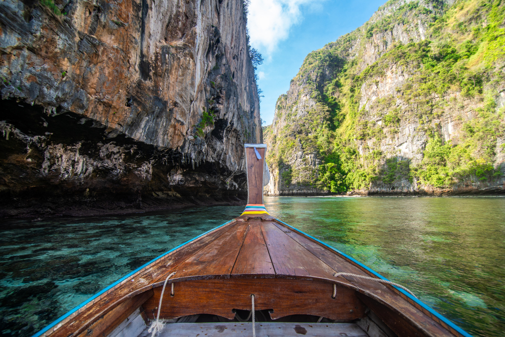 Thai beach with longtail boat and limestone cliffs