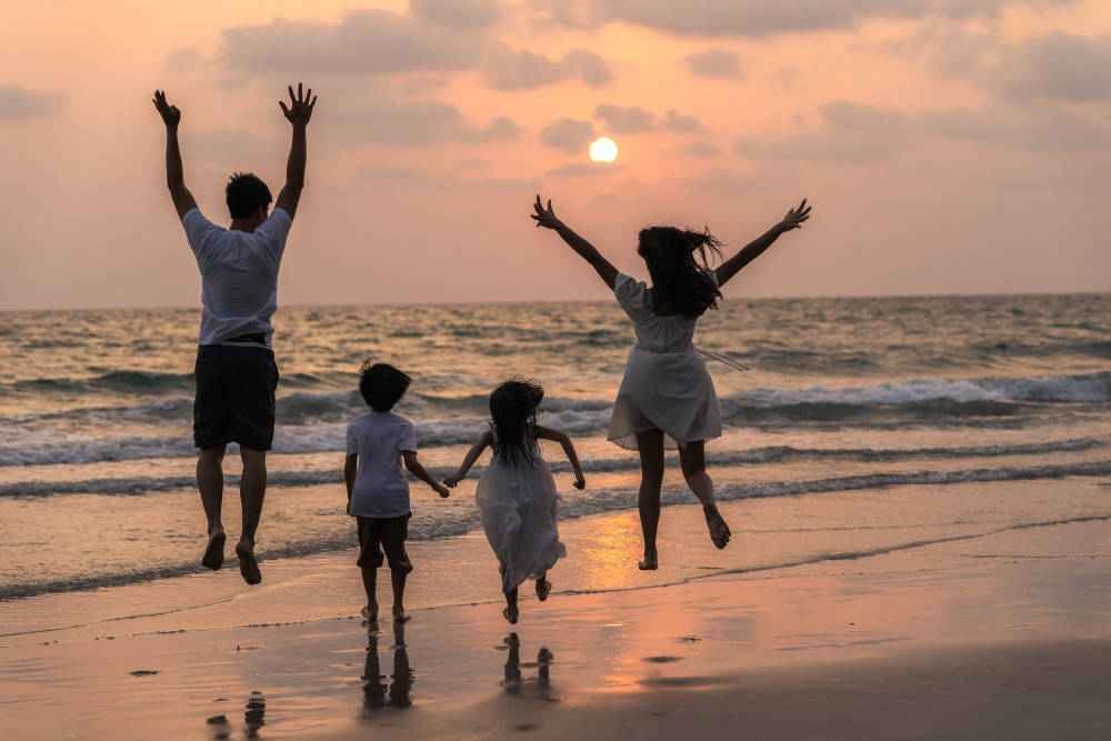 Family playing on a beach with clear blue water