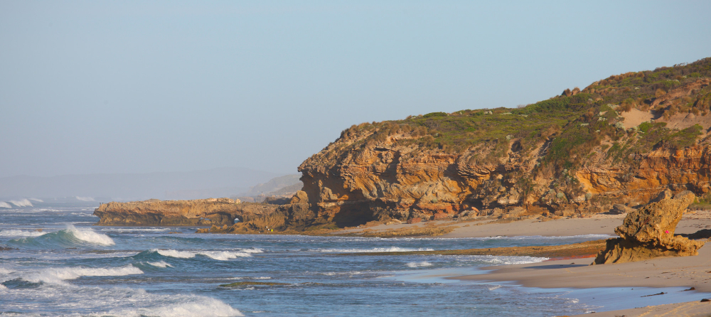 Golden sand beach with volcanic rocks and blue ocean