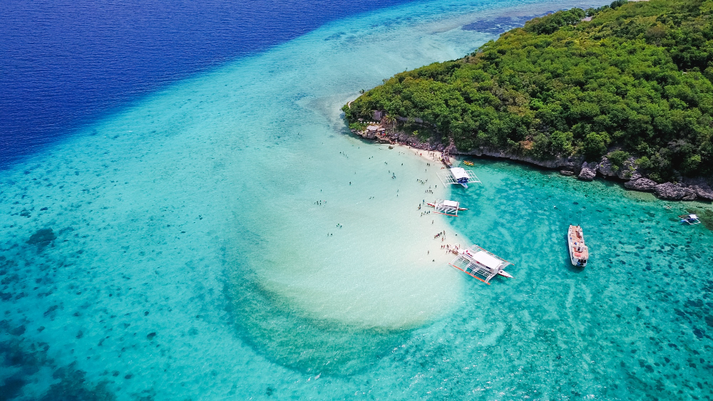 Aerial view of the Philippines archipelago with turquoise water surrounding lush green islands, showcasing the scale of island hopping travel